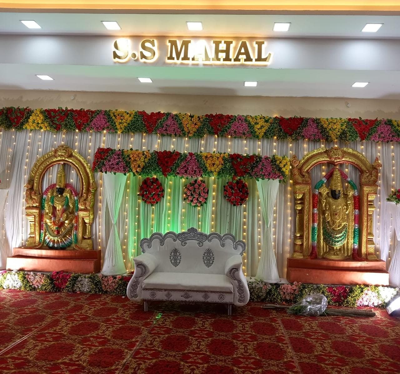 Traditional wedding stage with deities and flower garlands